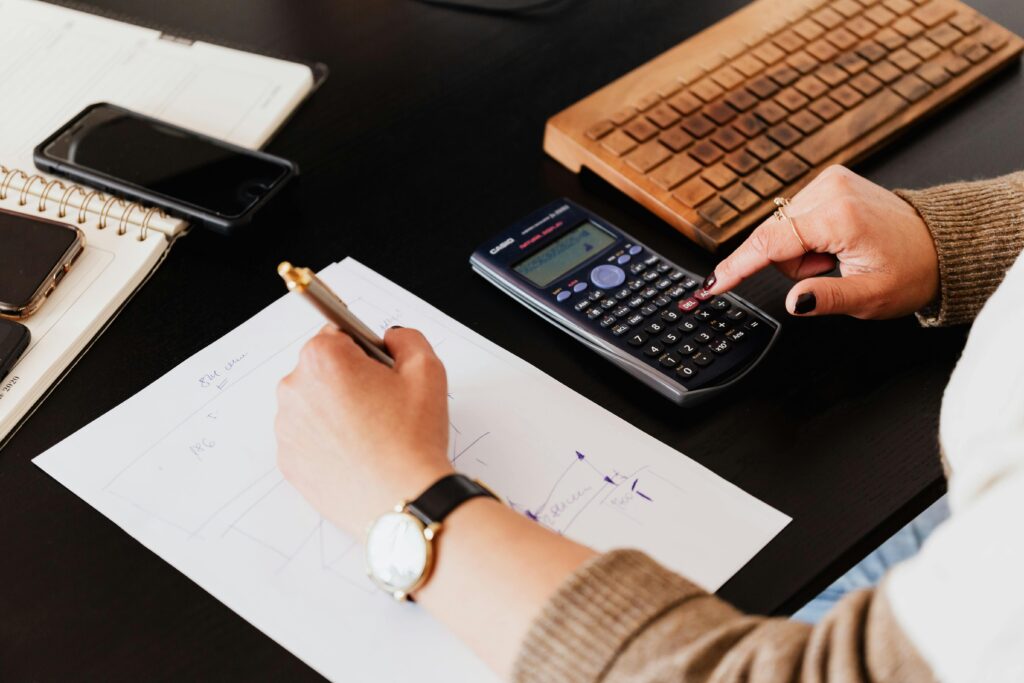 Homeowner calculating renovation costs with floor plans and budget sheet on table