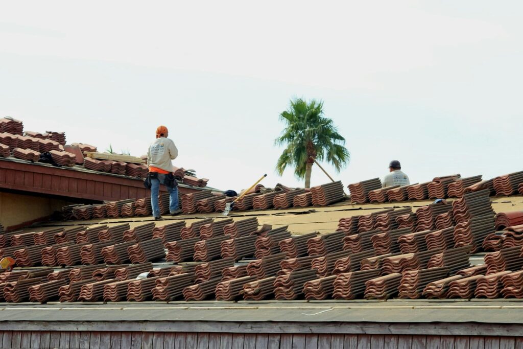 Roofers installing tile roofing on a home in Arizona, preparing for long-term protection against heat and roof weathering.
