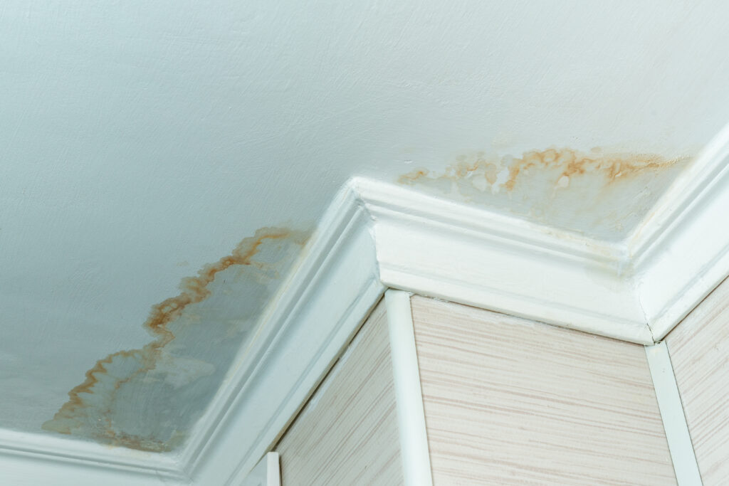 Interior ceiling corner with visible brown water stains indicating a roof leak in Phoenix home