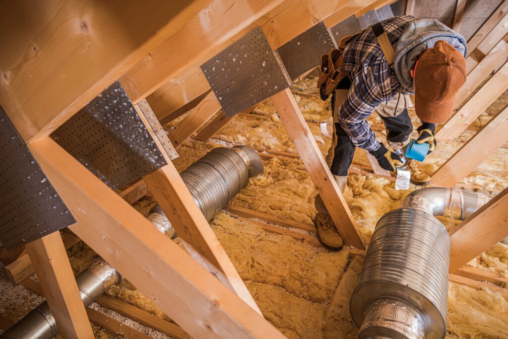 Contractor inspecting attic insulation and HVAC ductwork during a roof repair in Phoenix home.