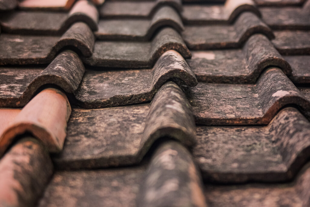 Close-up of sun-damaged roof tiles showing wear, cracks, and loss of granules due to UV exposure